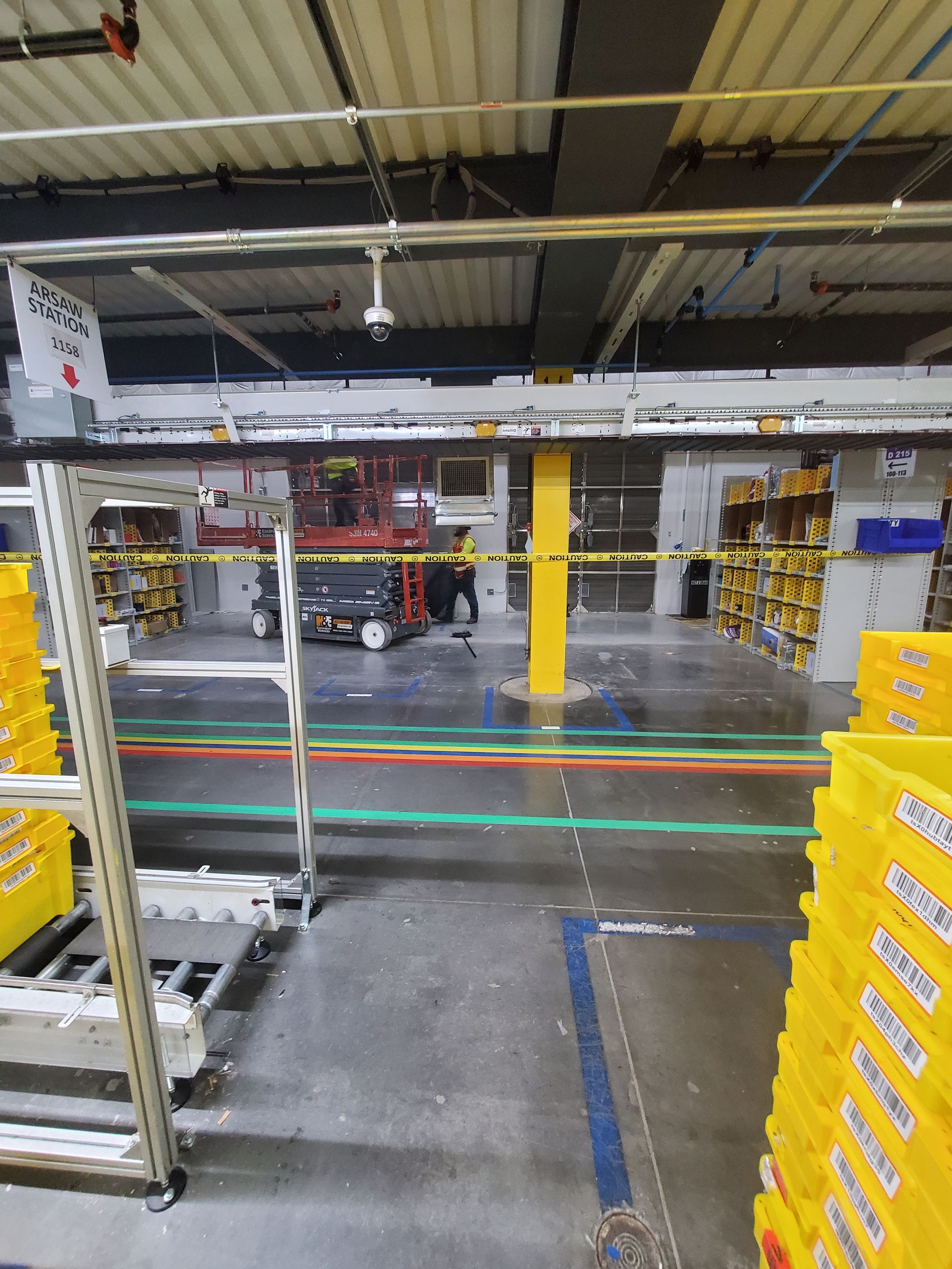 Warehouse interior with automated equipment, yellow bins, and a worker.