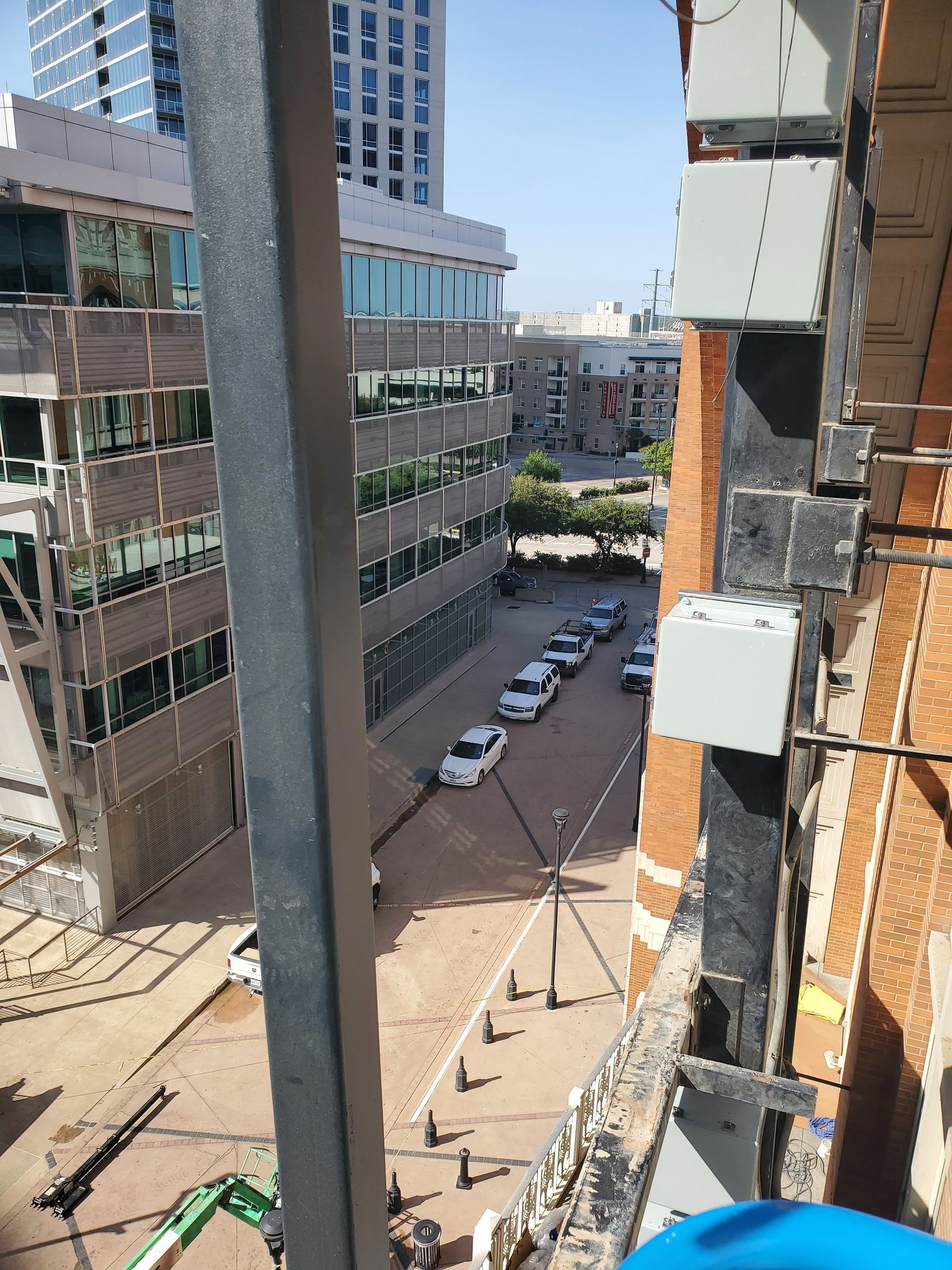 View of a city street lined with cars and buildings, taken from an elevated position.