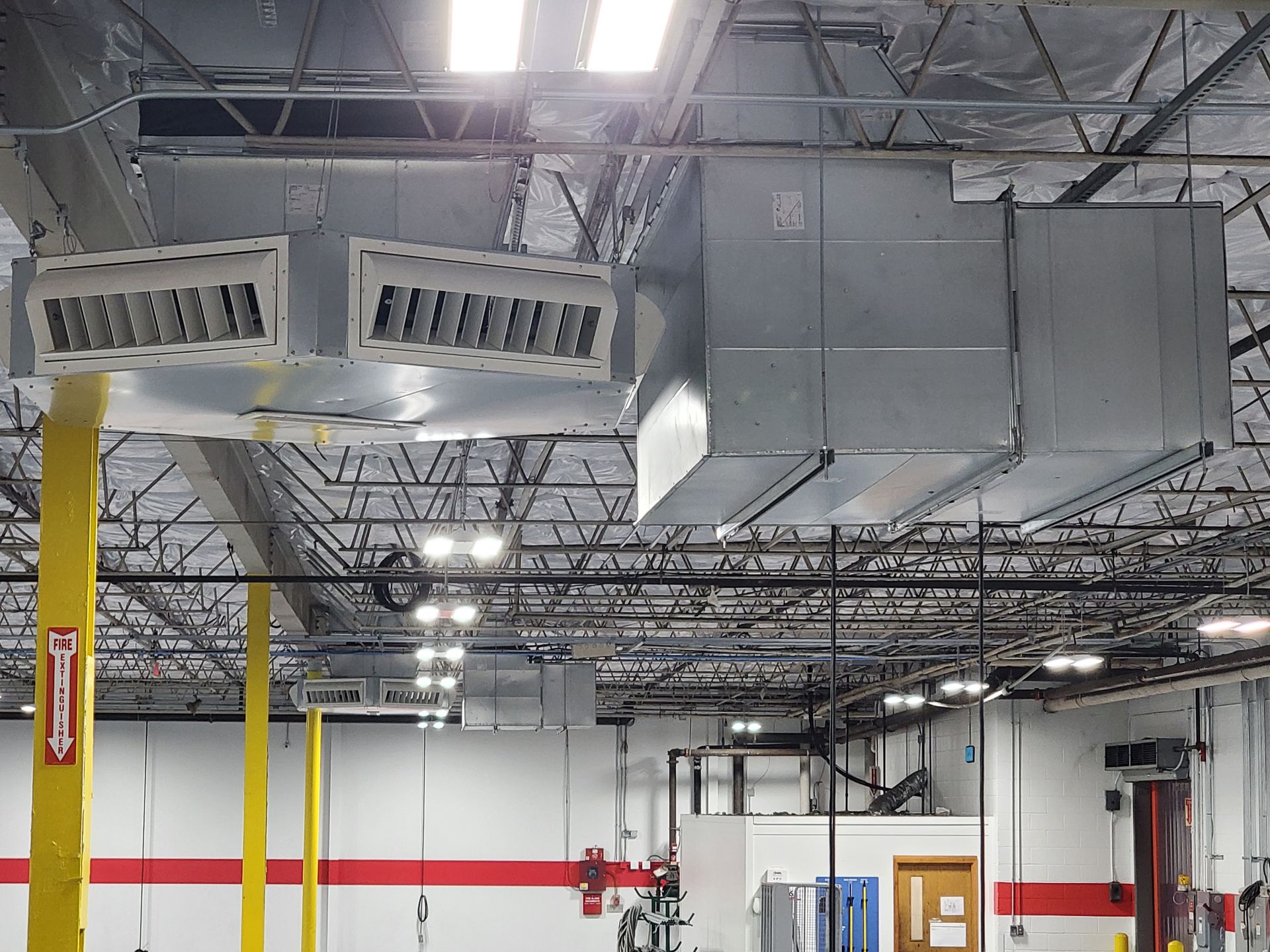 HVAC system in an industrial setting; includes ducts, vents, and overhead lighting.