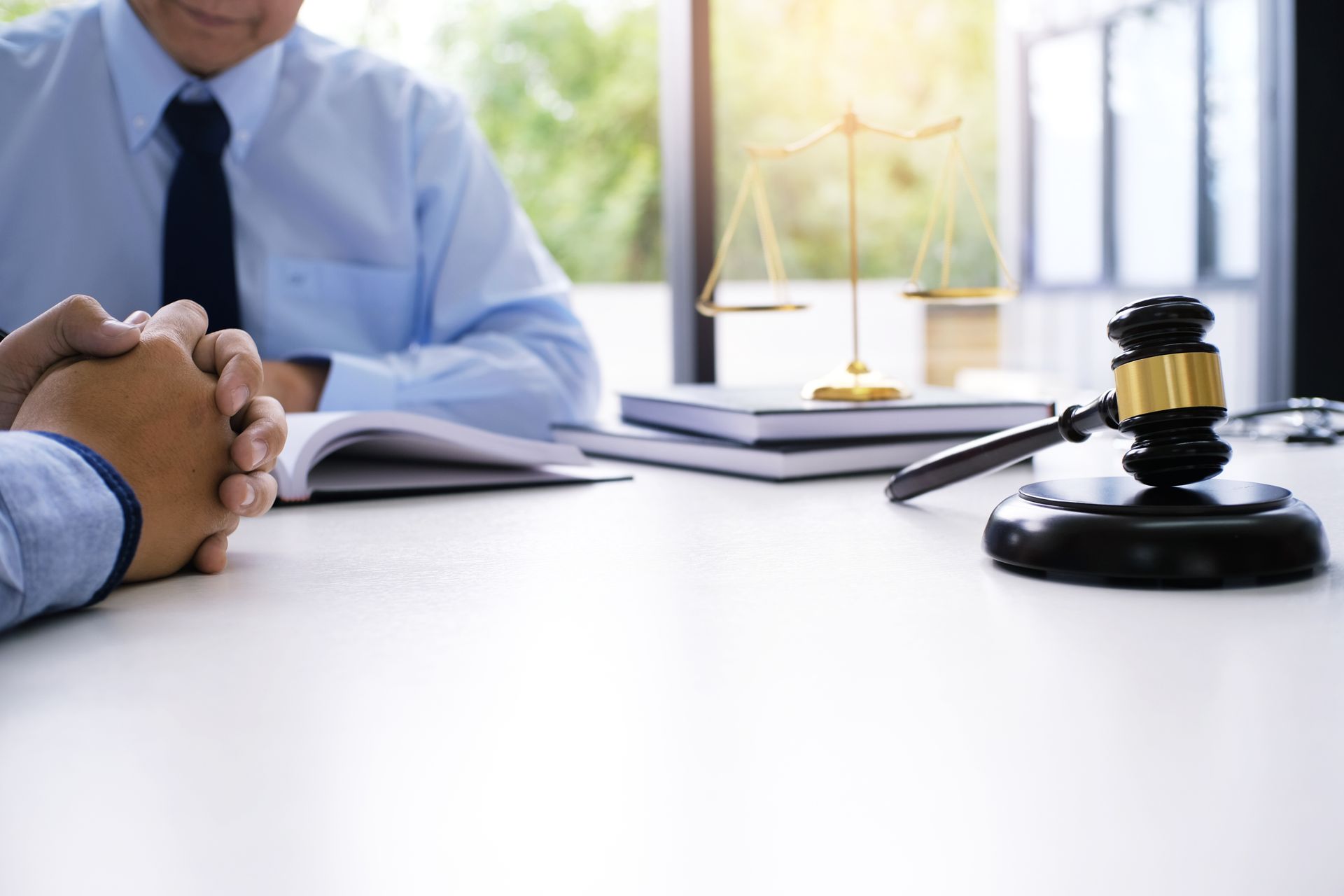 Lawyer with client; gavel on table, scales of justice in background.