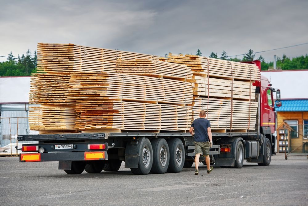 A Man is Standing Next to a Truck That is Loaded With Wood — Supersonic Couriers In Rockhampton, QLD