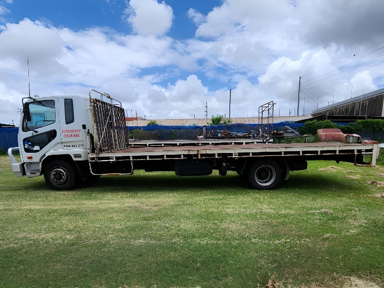 A flatbed truck is parked in a grassy field- Super Sonic Couriers in West Mackay, QLD