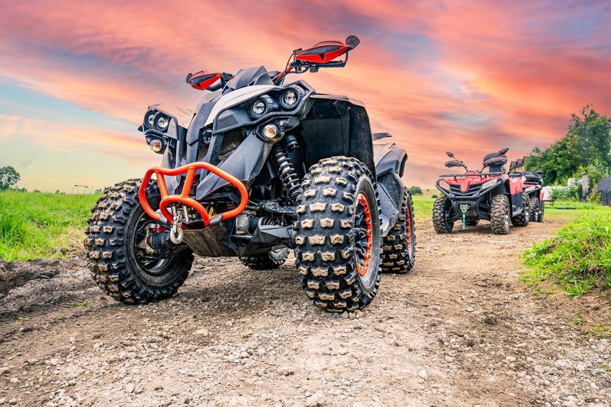 Two atvs are parked on a dirt road.