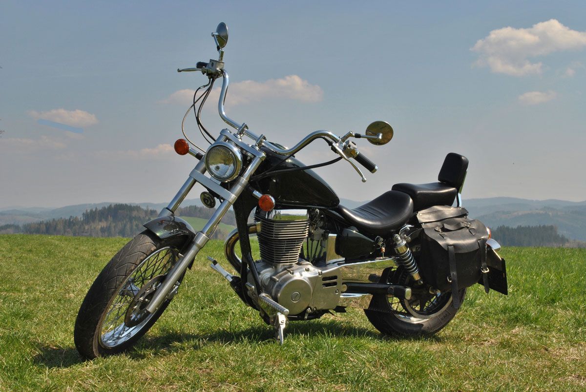 A black motorcycle is parked in a grassy field.