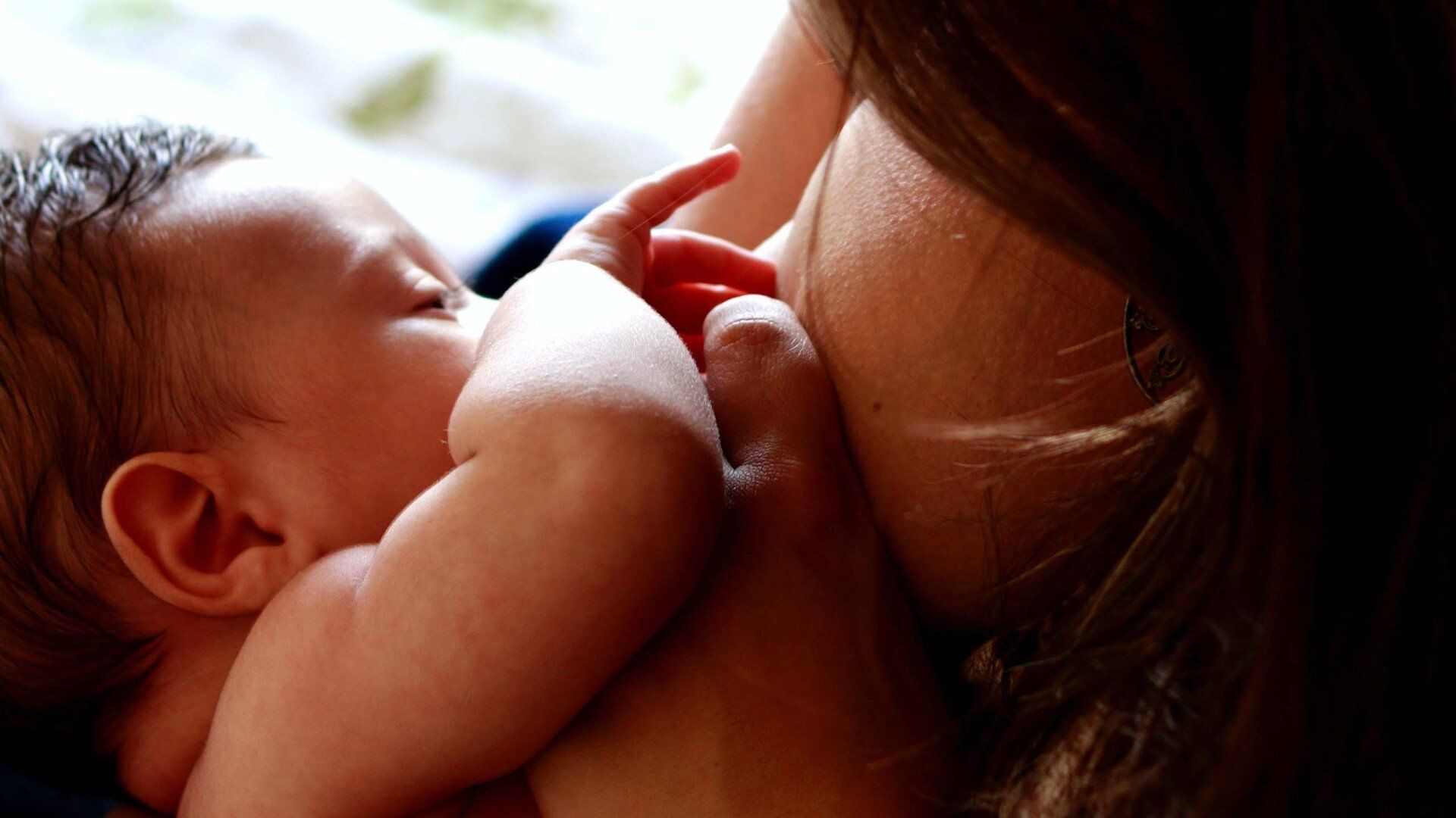 Foto de bebê sendo amamentado, por Luiza Braun