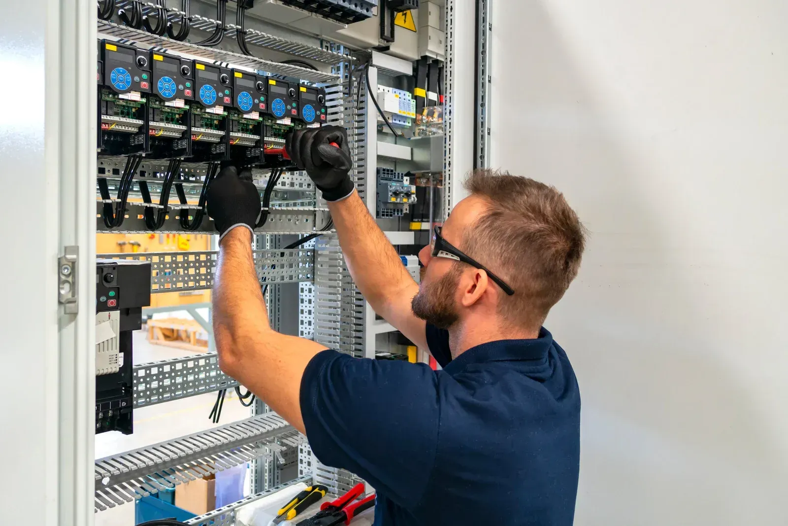 A man is working on an electrical box in a factory.