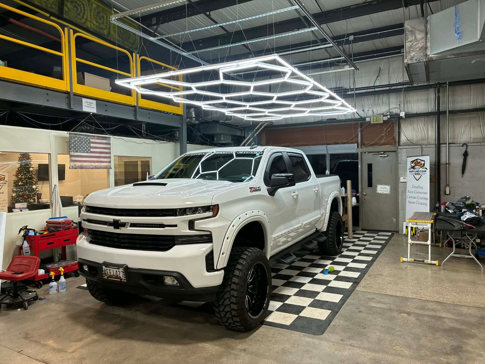 Man using a power buffer on a car in a garage.