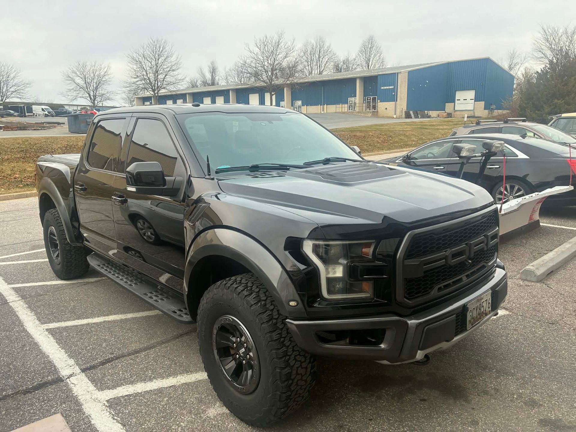 Black Ford Raptor pickup truck parked outside a building.