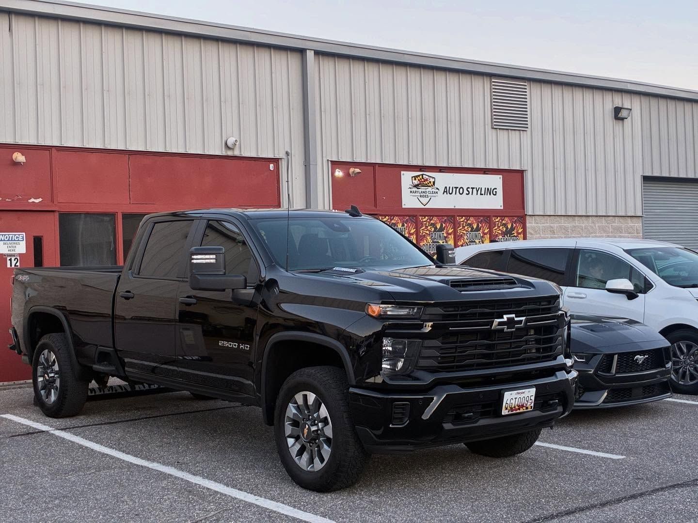 Black Chevrolet truck parked outside a building, next to a white SUV and a black sedan.