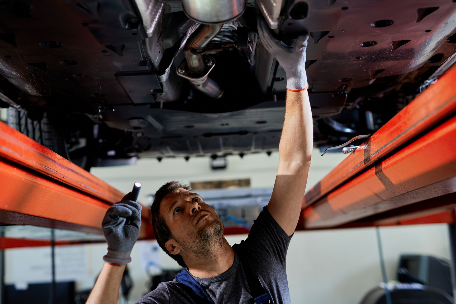 A man polishes a black car with a power tool in a garage-like setting.