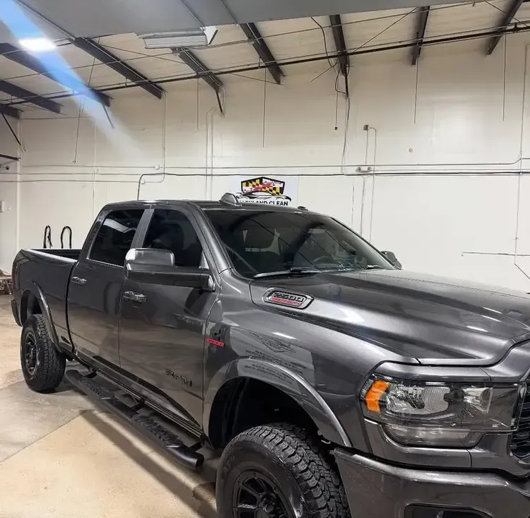 Dark gray pickup truck parked inside a garage; overhead lighting.