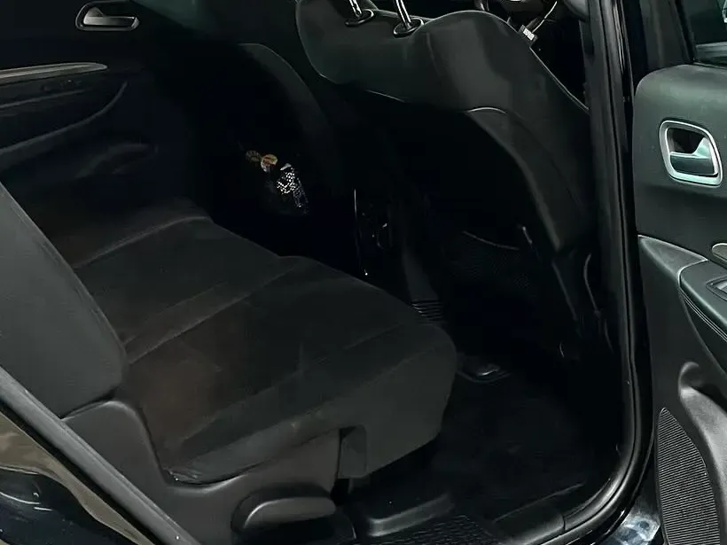 Black car interior with rear seats, black floor mats, and door panel.