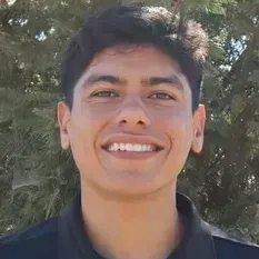 Smiling person in a black shirt outdoors with trees in the background