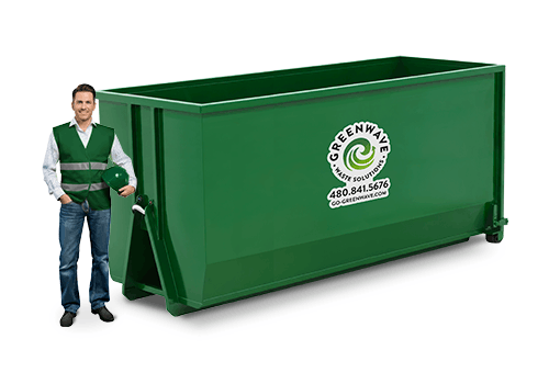 A silhouette of a man standing next to a green dumpster.