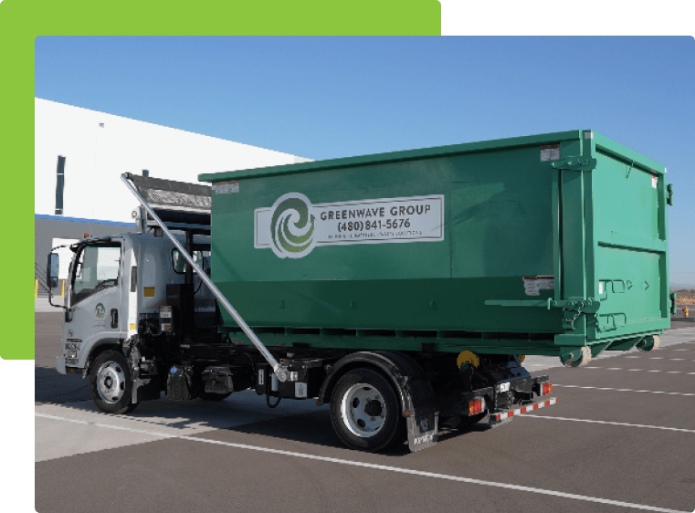 A green dumpster rental truck is parked in a parking lot.