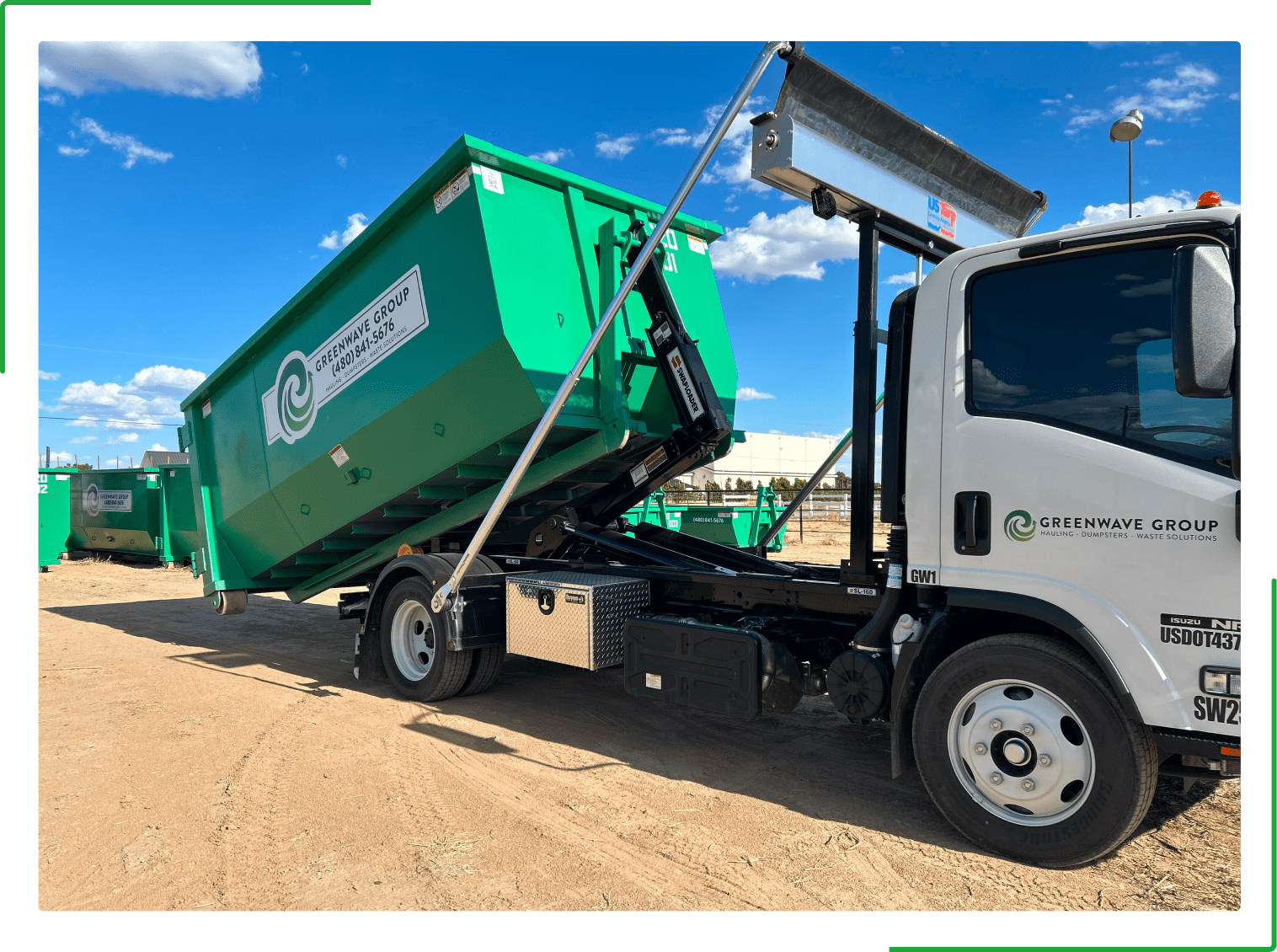 A green dumpster rental truck is parked in a parking lot.