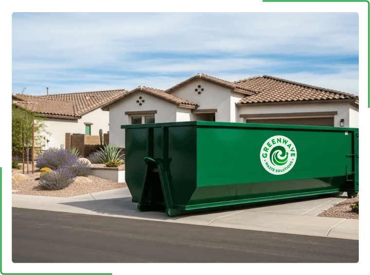 A green dumpster filled with cardboard boxes is sitting on the side of the road.