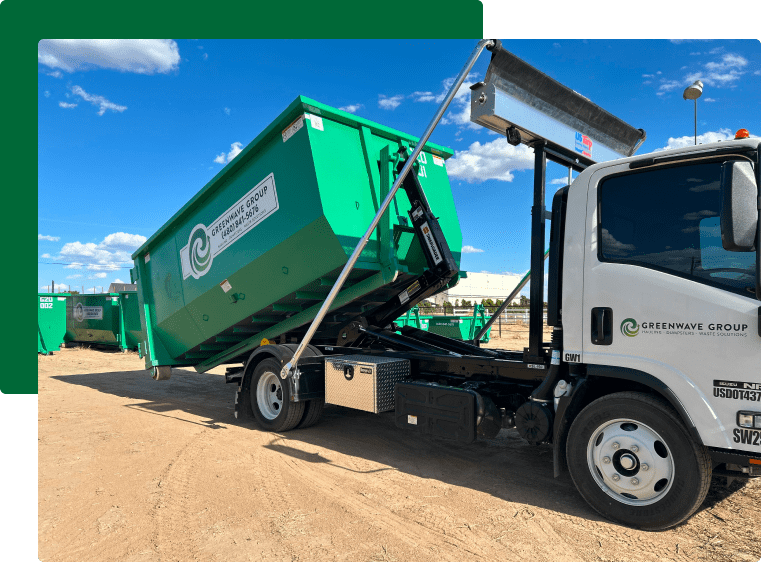 A green dumpster filled with cardboard boxes is sitting on the side of the road.
