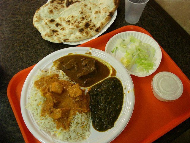 A tray with Indian food: rice, curry, spinach, naan, and salad.