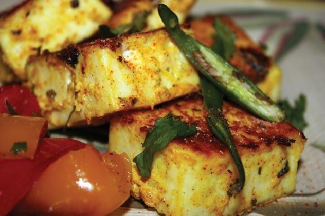 Golden-brown paneer cubes with red and orange bell peppers, garnished with green chili and cilantro.