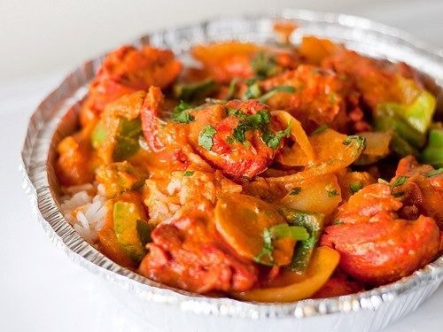 Chicken tikka masala with rice and vegetables in a foil bowl.