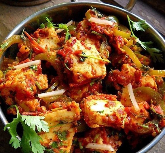 Paneer tikka masala in a metal bowl with bell peppers, cilantro and onions.