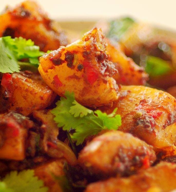 Close-up of potato dish with red spice and cilantro garnish.