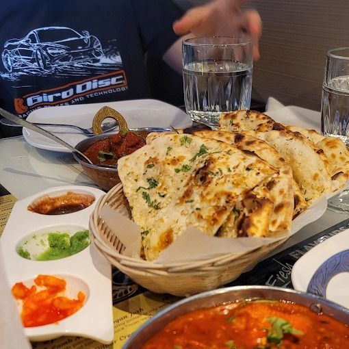 Indian meal with naan bread, sauces, and red curry.