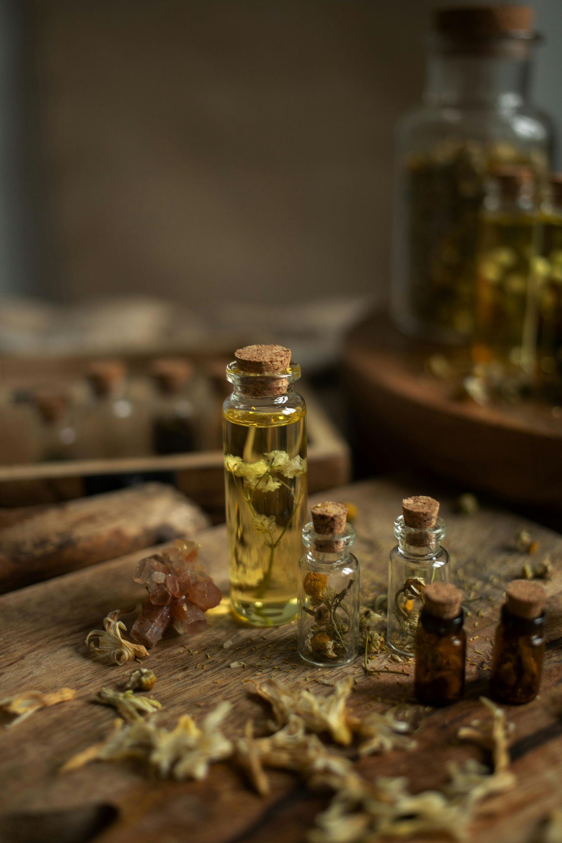Pequenos frascos de vidro com rolhas cheios de óleos de ervas sobre uma superfície de madeira, 
