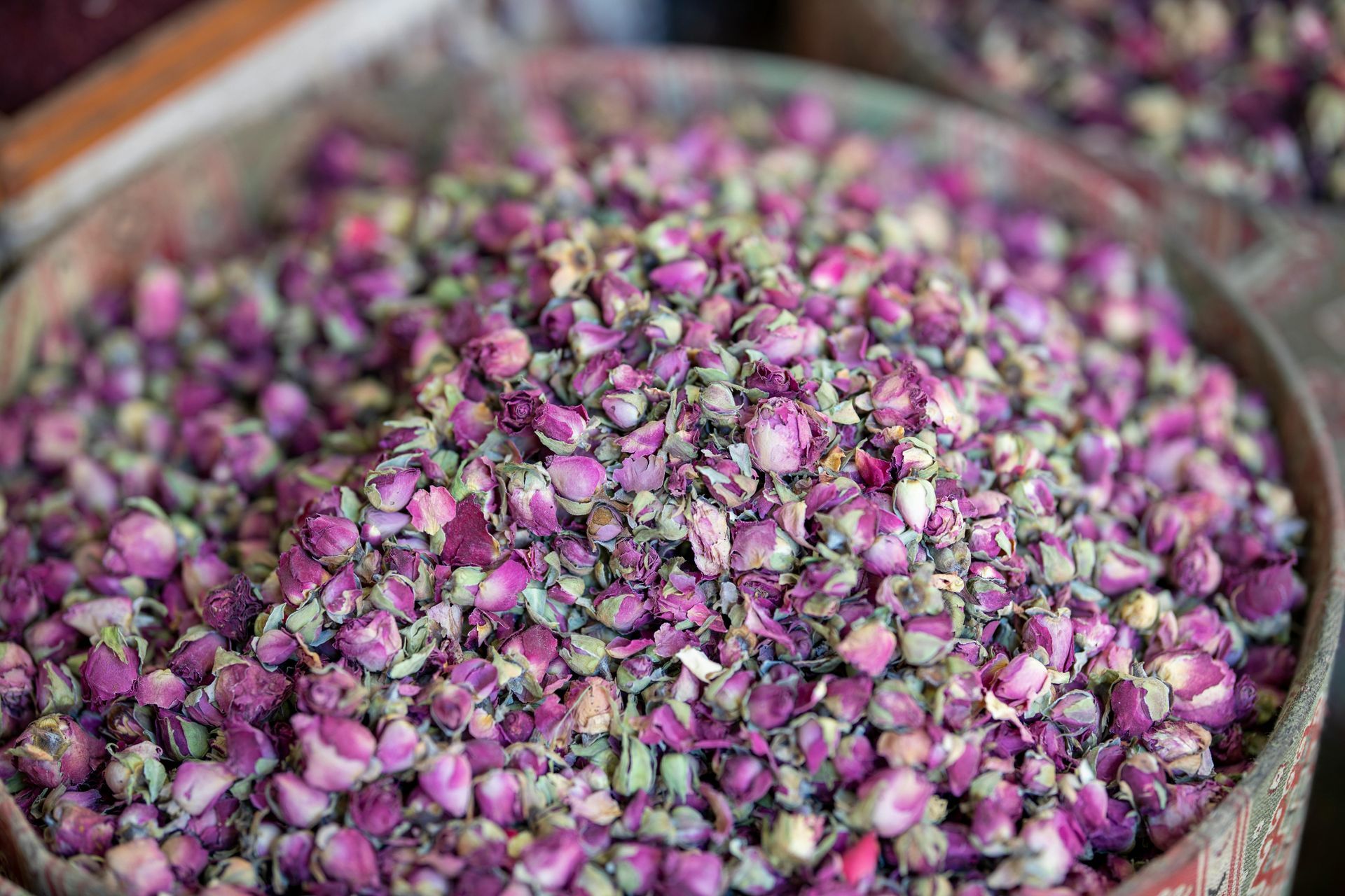 Botões de rosas secas em uma grande cesta de vime, prontos para venda no mercado.