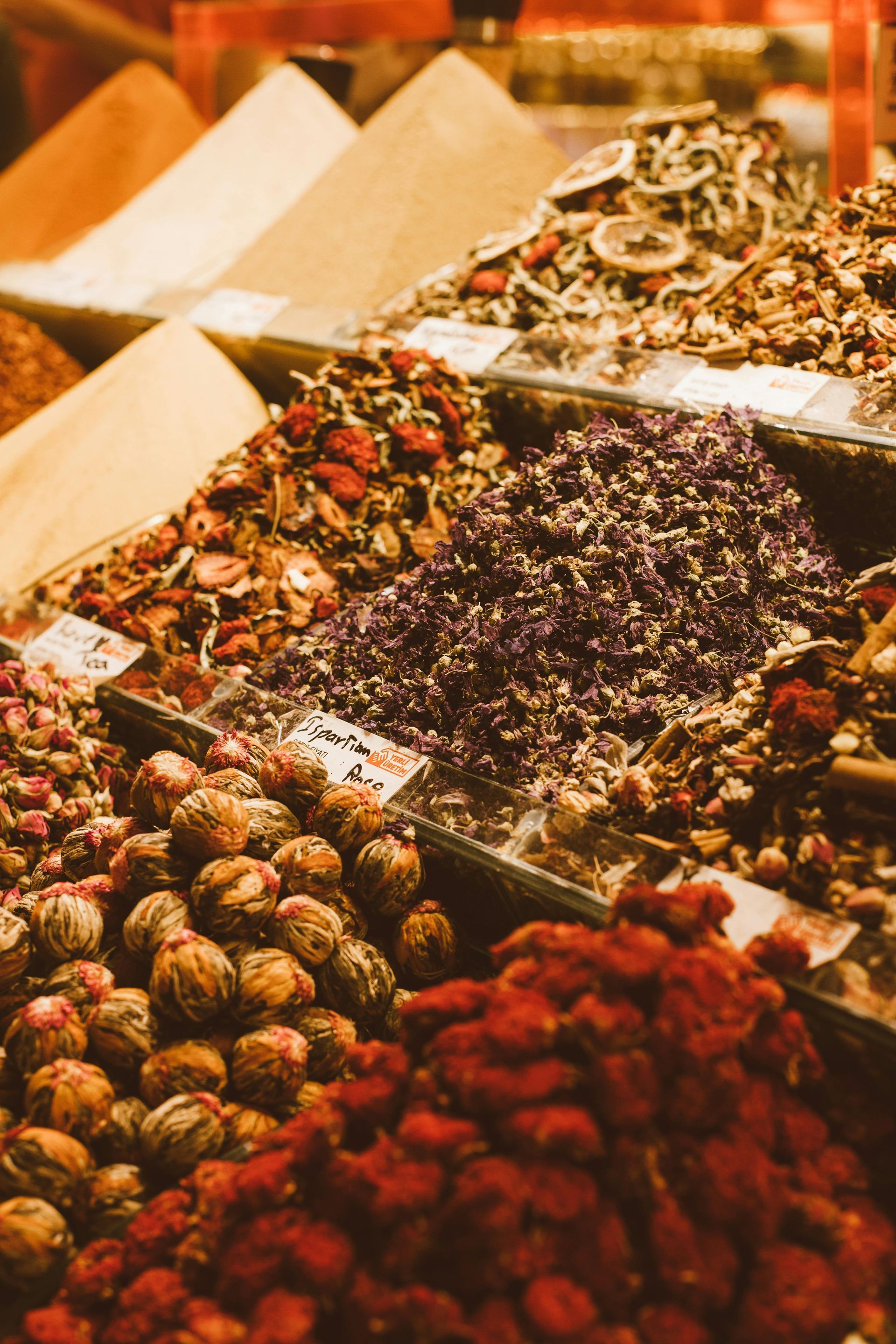 Uma exibição vibrante de especiarias e chás em uma barraca de mercado; várias cores, texturas e formas em um close-up.