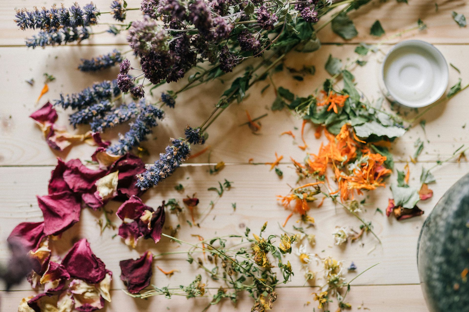 Ervas e pétalas de flores em tons de roxo, laranja e vermelho 