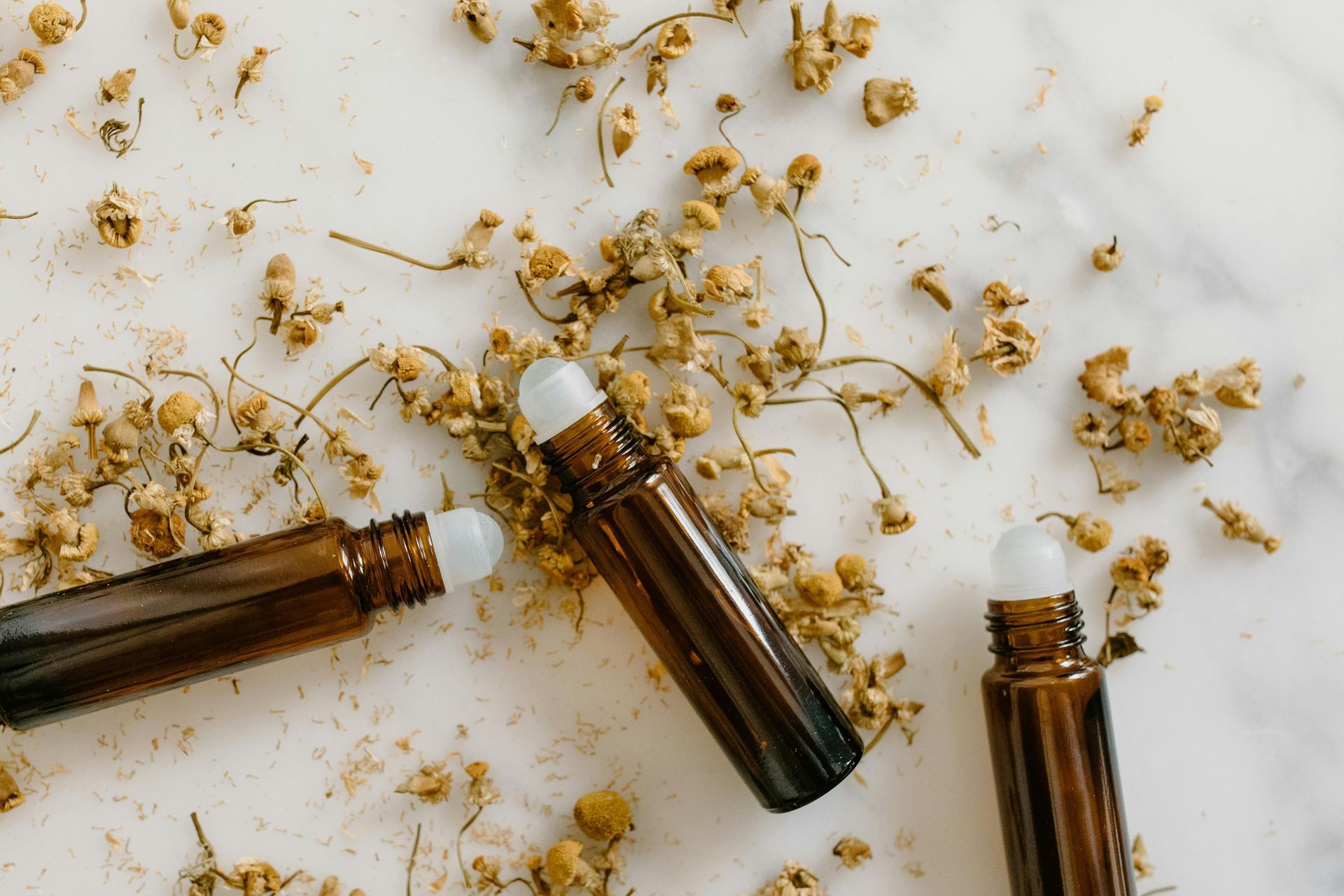 Três frascos roll-on marrons para óleos essenciais com tampas brancas,