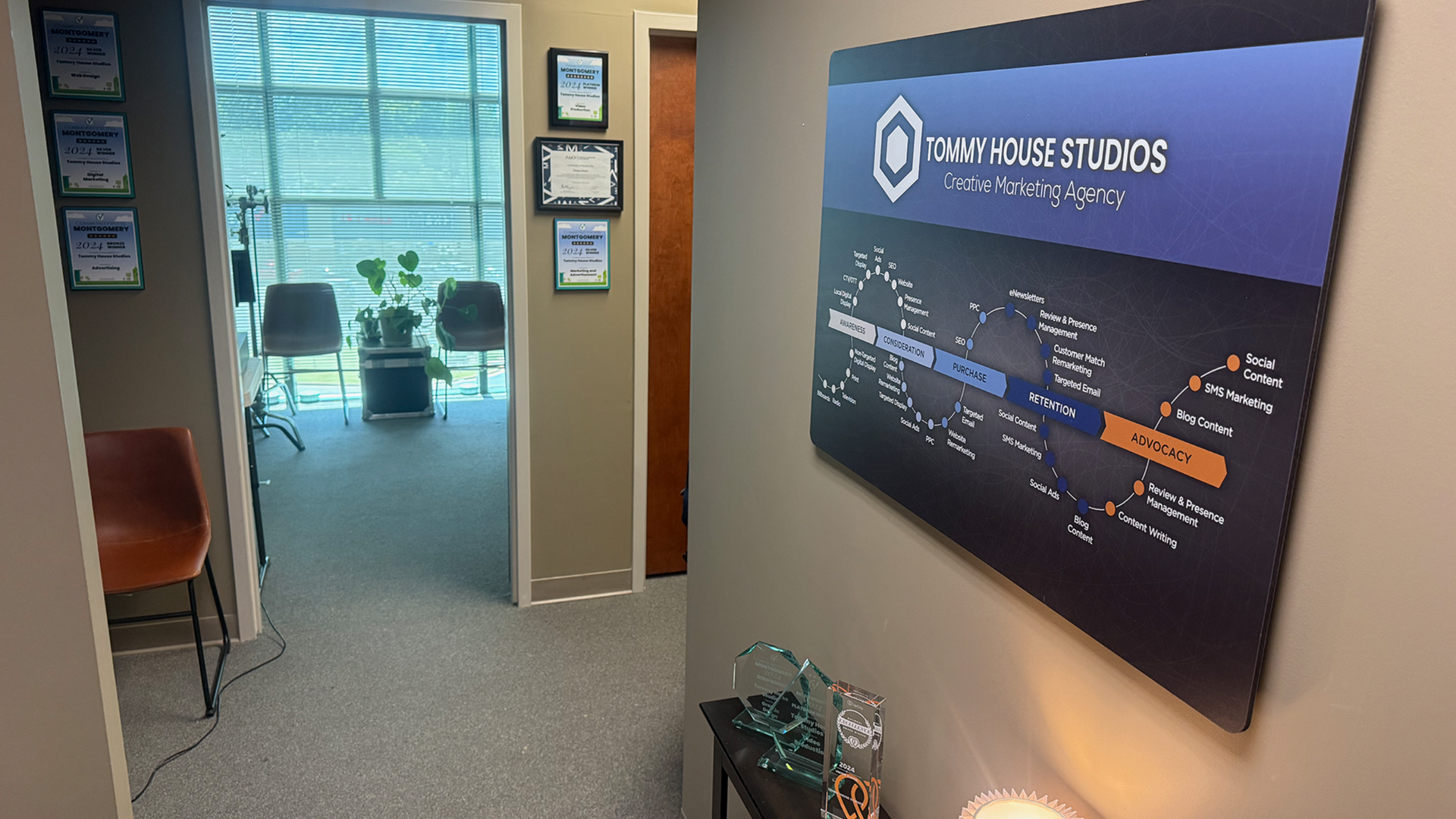 Office hallway with sign for Tommy House Studios, doorway to waiting area with chairs.