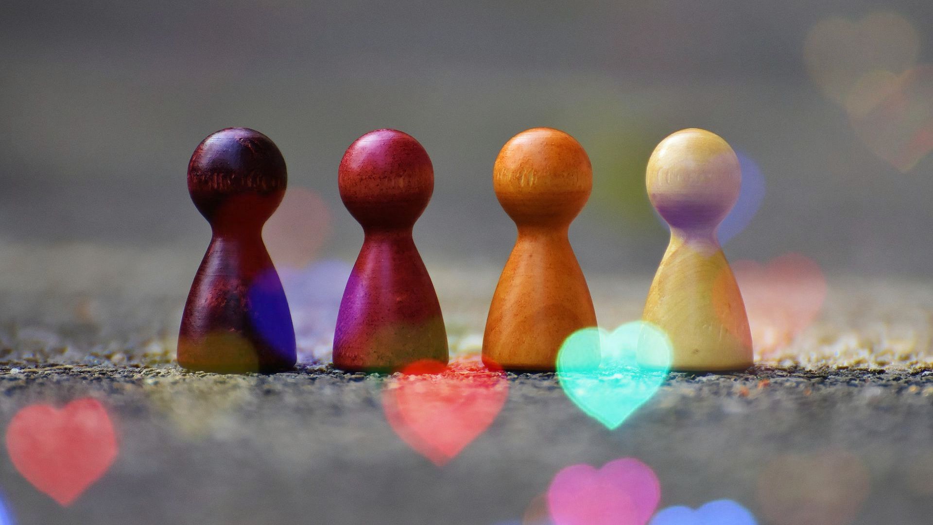 Four wooden peg dolls are sitting next to each other on the ground.