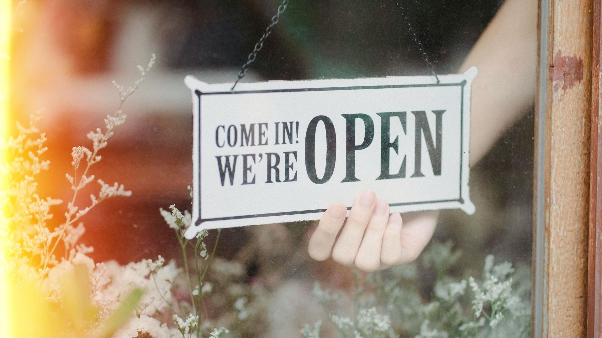 A person is holding a sign that says `` come in we 're open ''.