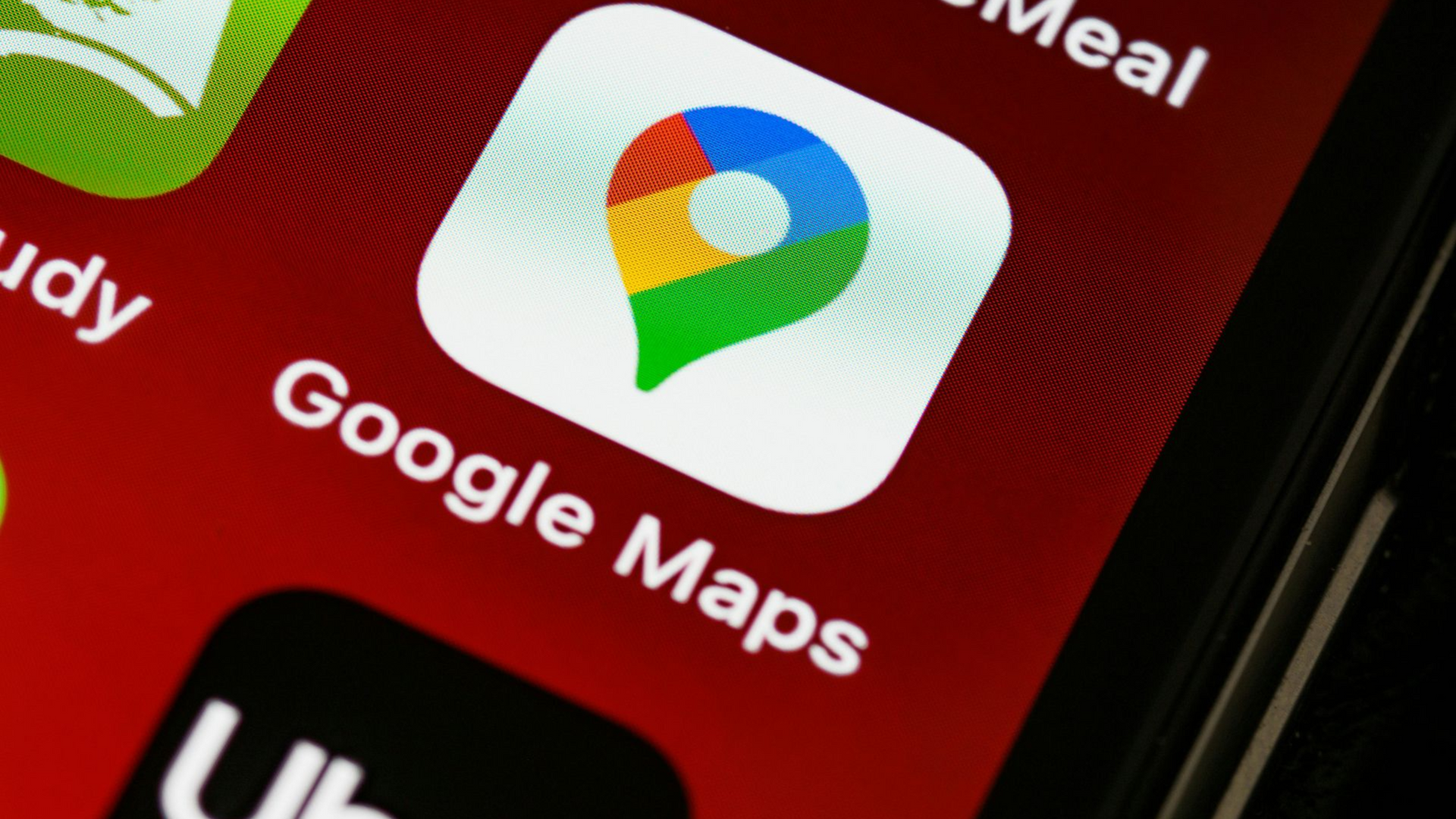 Google Maps app icon on a phone screen, featuring a colorful pin on a white square, red background.