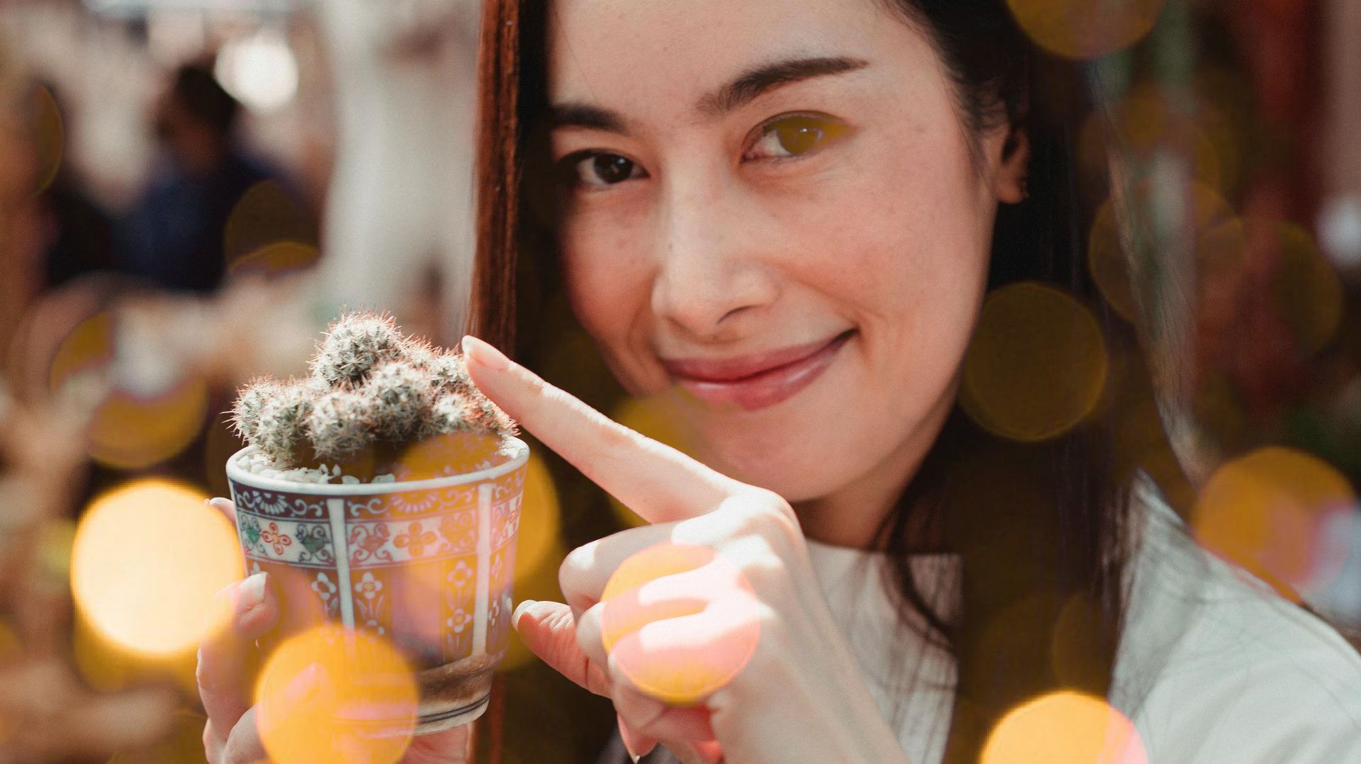 A woman is holding a cup with a cactus in it.