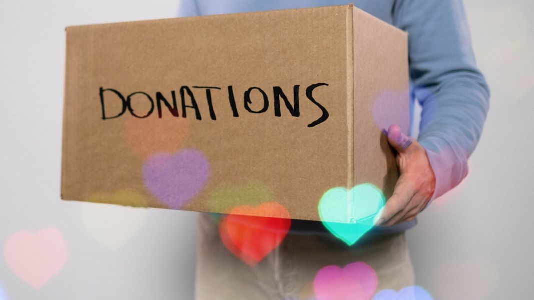 a person is holding a cardboard box that says donations