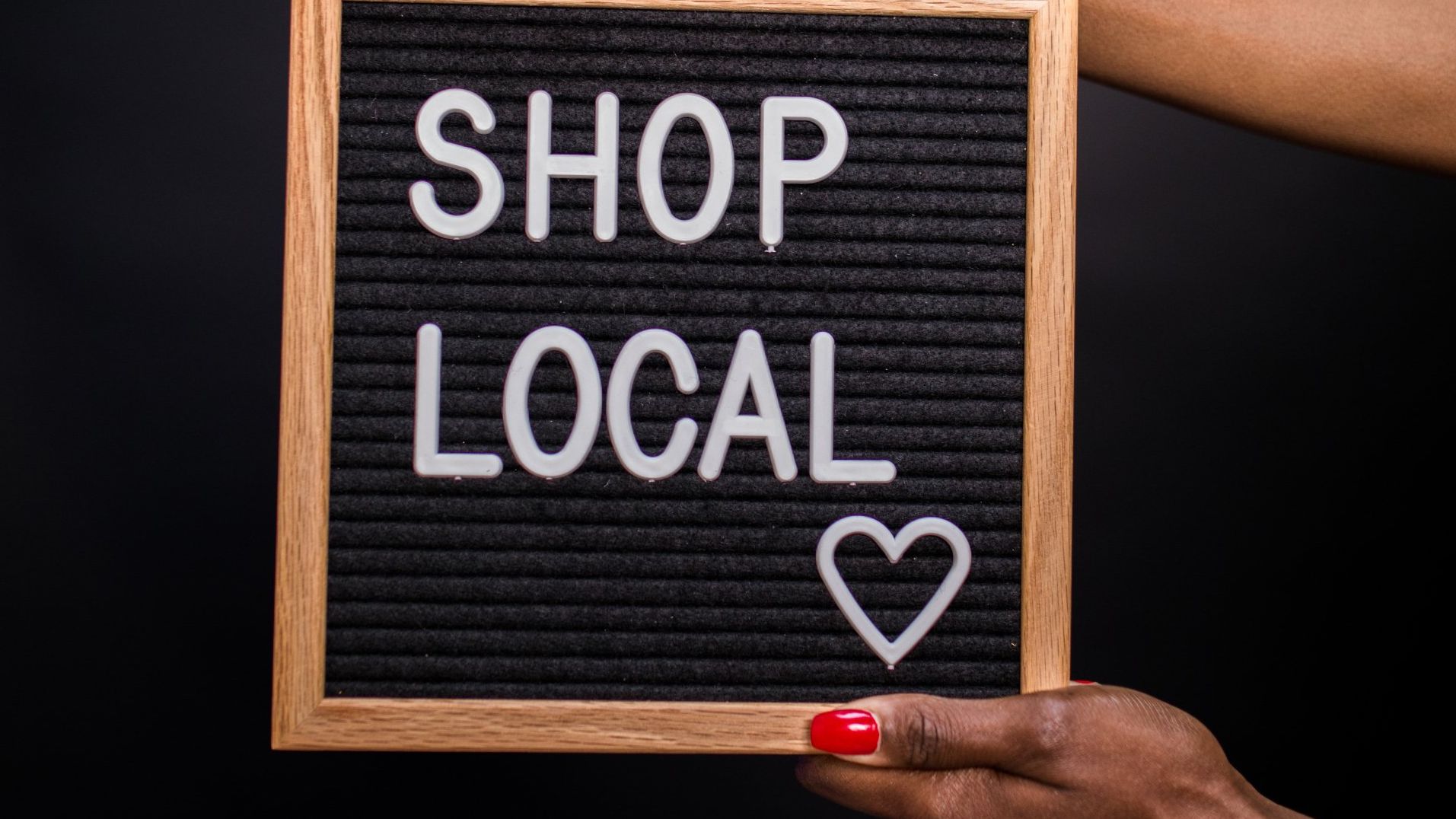 A woman is holding a sign that says `` shop local ''.