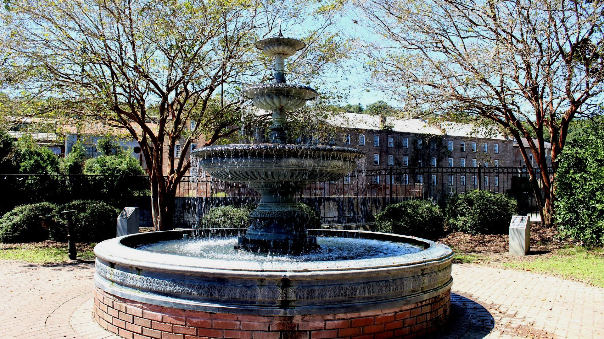 A large fountain is surrounded by trees in a park.