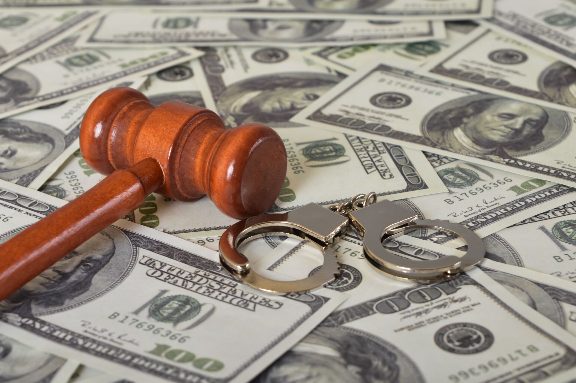handcuff and judge gavel on the top of dollar bills