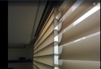 Primer plano de persianas en capas de color beige, con luz brillando a través de las lamas.