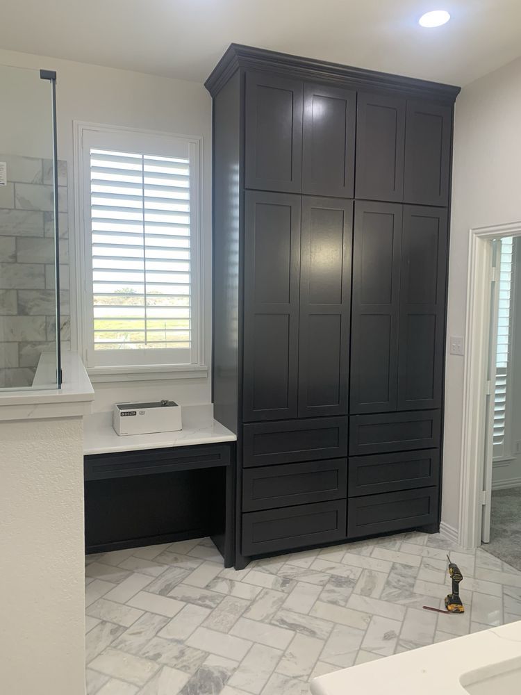 Modern bathroom with a large dark vanity cabinet, white countertop, and marble-patterned floor tiles.