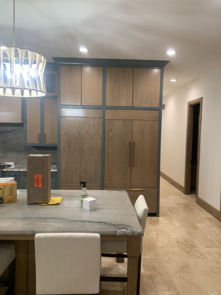 Modern kitchen with wood cabinets, island seating, and a hallway doorway.