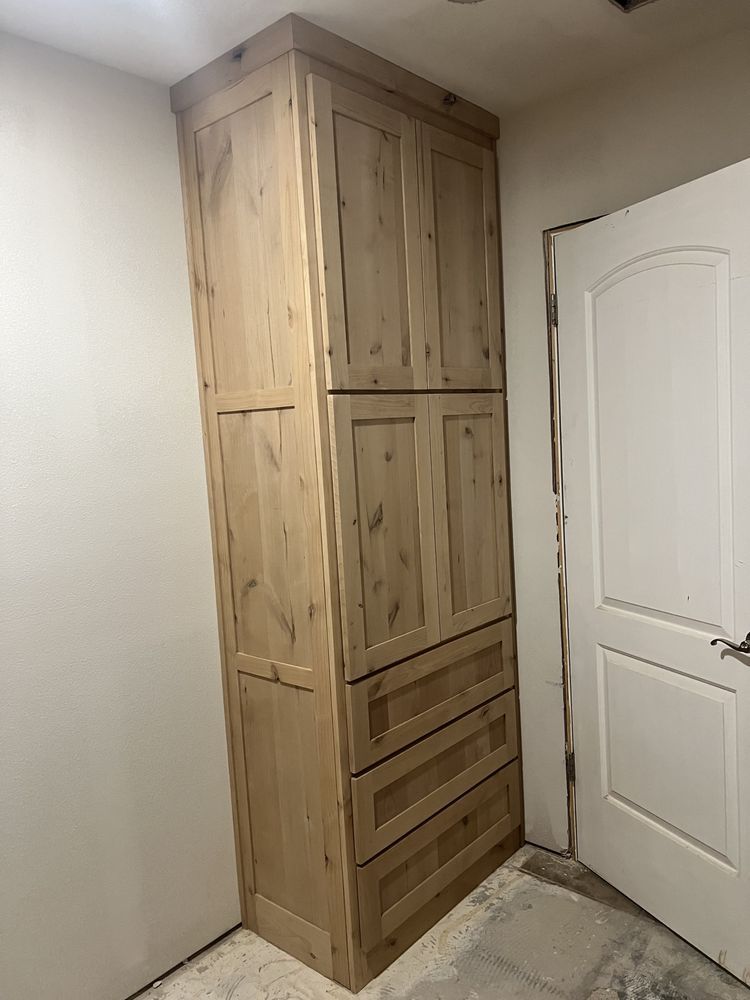 Tall light-wood storage cabinet beside a white interior door in a small room