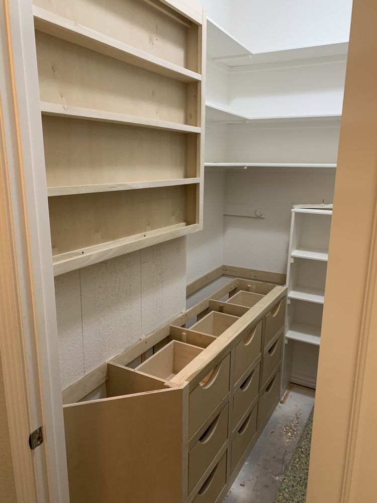 Empty walk-in closet under construction with built-in shelving and unfinished drawers