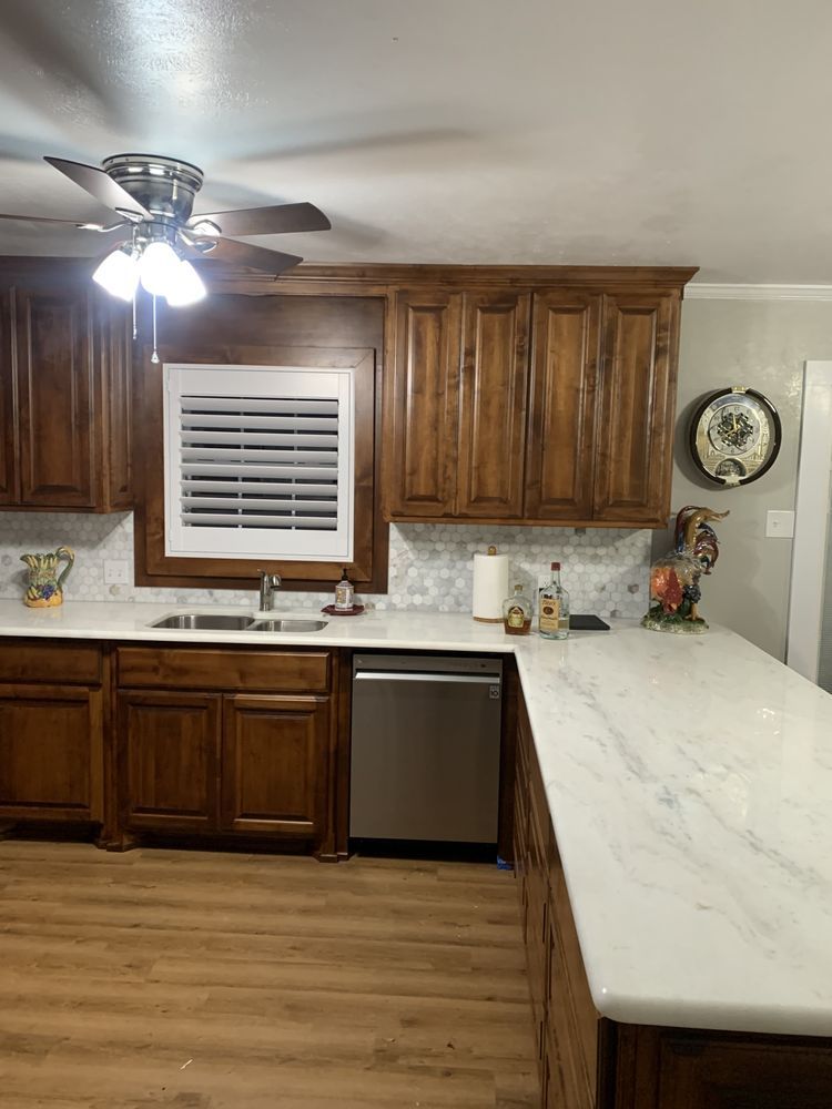 Kitchen with brown cabinets, white countertops, and a window above the sink with blinds.