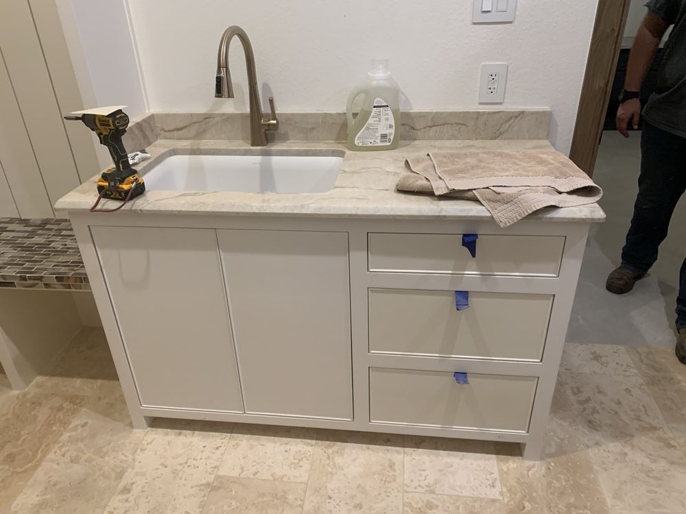Partially installed bathroom vanity with sink, faucet, drawers, and tools on top.