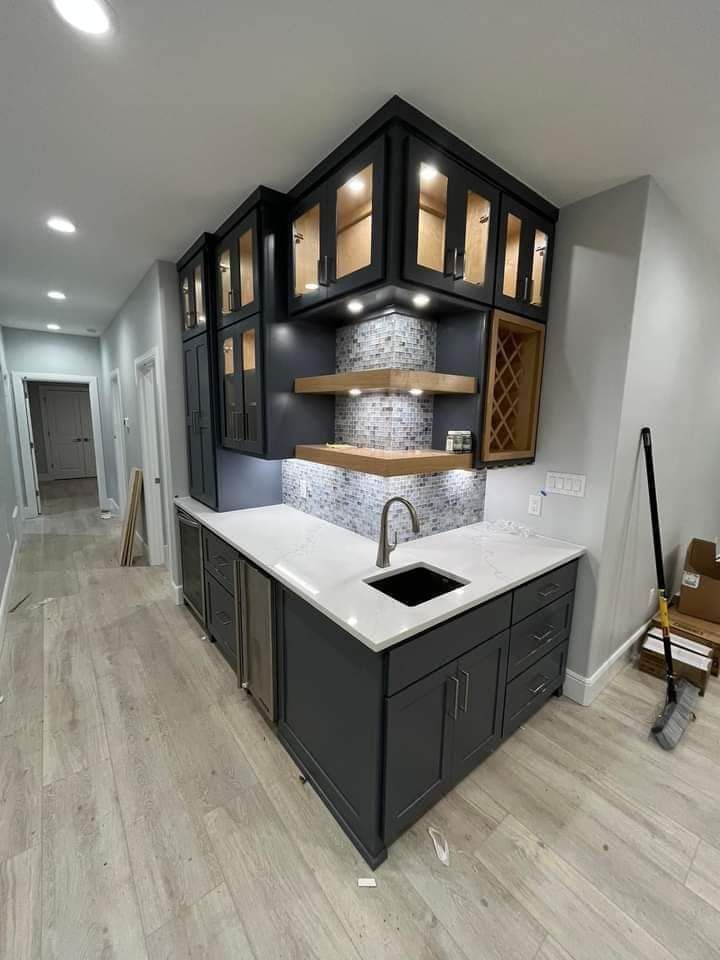Modern kitchen with dark cabinets, white countertops, and a central sink under geometric glass-front uppers